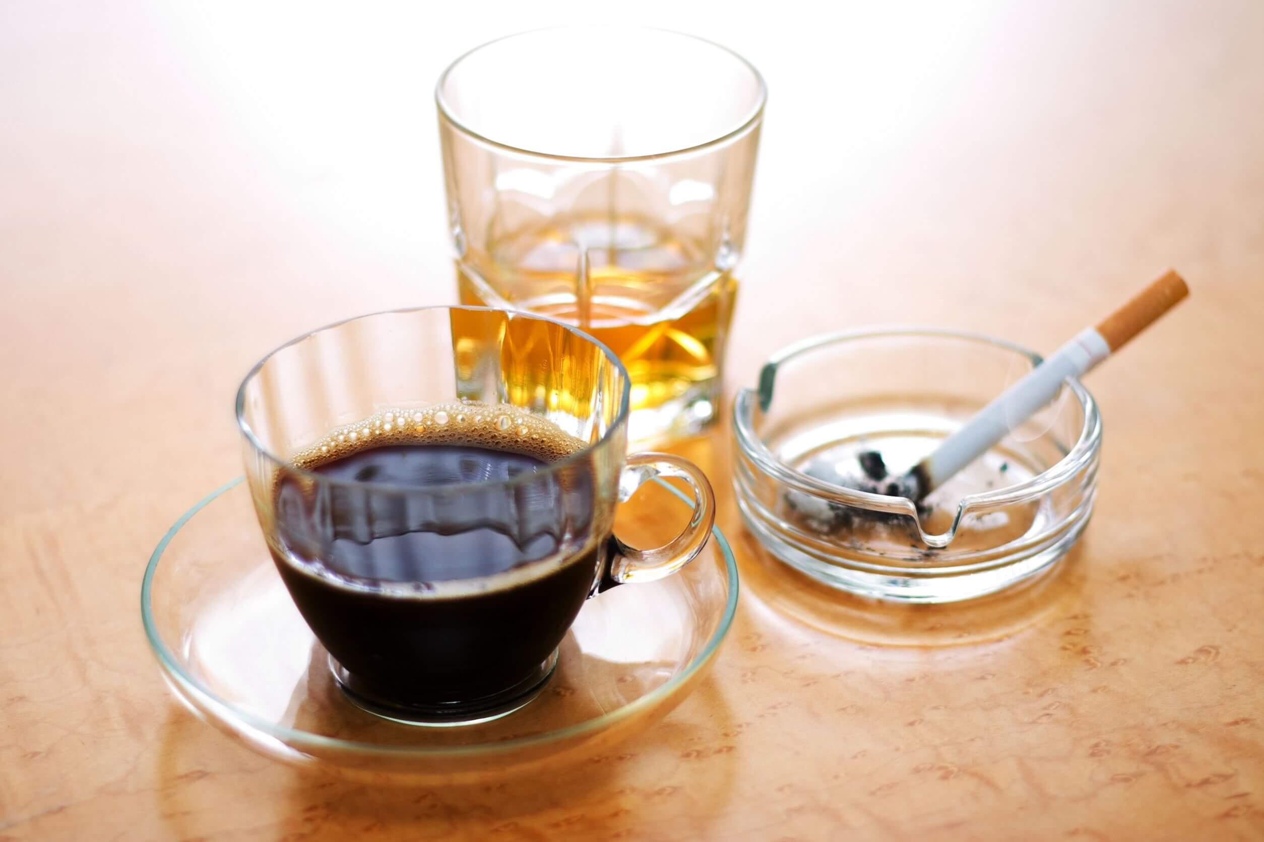 Šálka kávy, pohár s alkoholom a cigareta