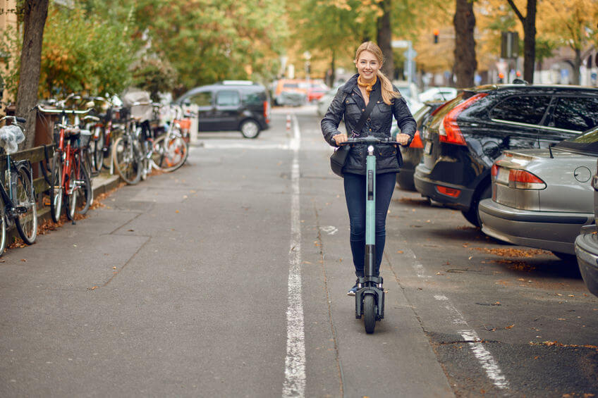 Žena jazdiaca po meste na elektrokolobežke.