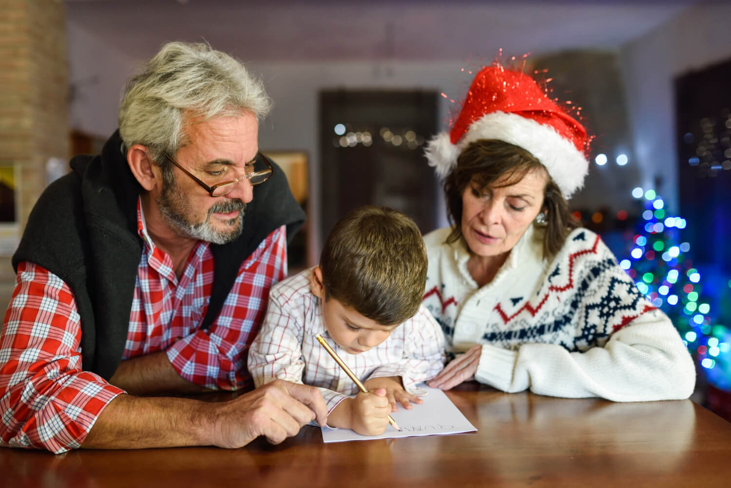 dieťa so starými rodičmi spolu píšu vianočný list pre Ježiška